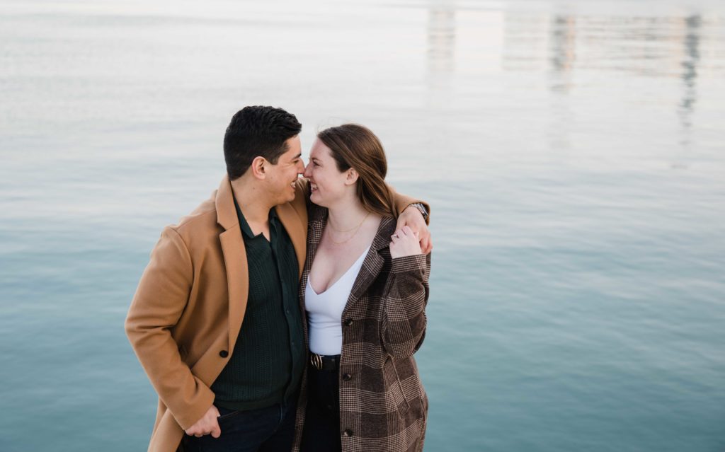 Engaged couple smiling in front of Lake Michigan